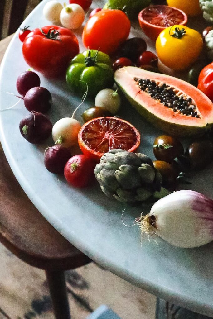 Bunch of various ripe exotic fruits and ripe healthy vegetables placed on marble table in light kitchen during harvest season